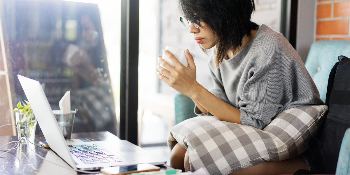 Woman Drinking coffee working at home on laptop